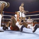 Muhammad Ali watches on as George Foreman struggles to get up after being knocked out.