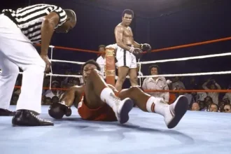 Muhammad Ali watches on as George Foreman struggles to get up after being knocked out.