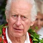 King Charles III in a white shirt and a garland of dried fruits from the pandanus tree put around his neck on his visit to Samoa.