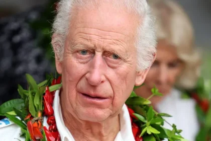 King Charles III in a white shirt and a garland of dried fruits from the pandanus tree put around his neck on his visit to Samoa.