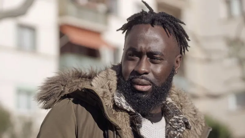 A close-up picture of Menka Gomis with short dreadlocks and a brown winter jacket