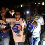 A group of UDC supporters in their party paraphernalia celebrating in the nght.