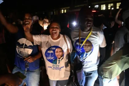 A group of UDC supporters in their party paraphernalia celebrating in the nght.