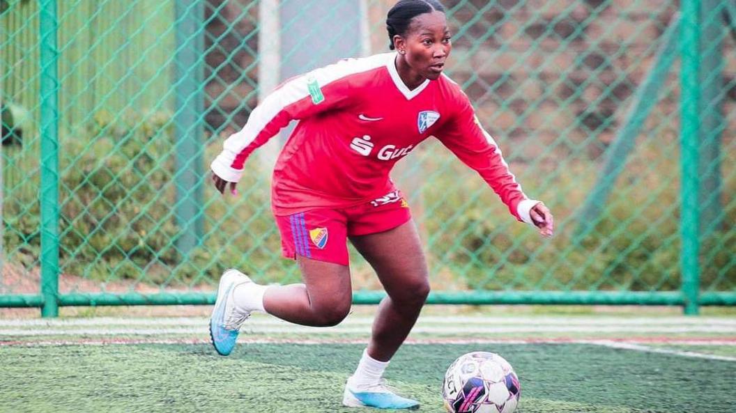 Kenya women's football player Esse Akida in red kit with the ball at her feet readying for a pass during a training session at an artificial football pitch in Nairobi